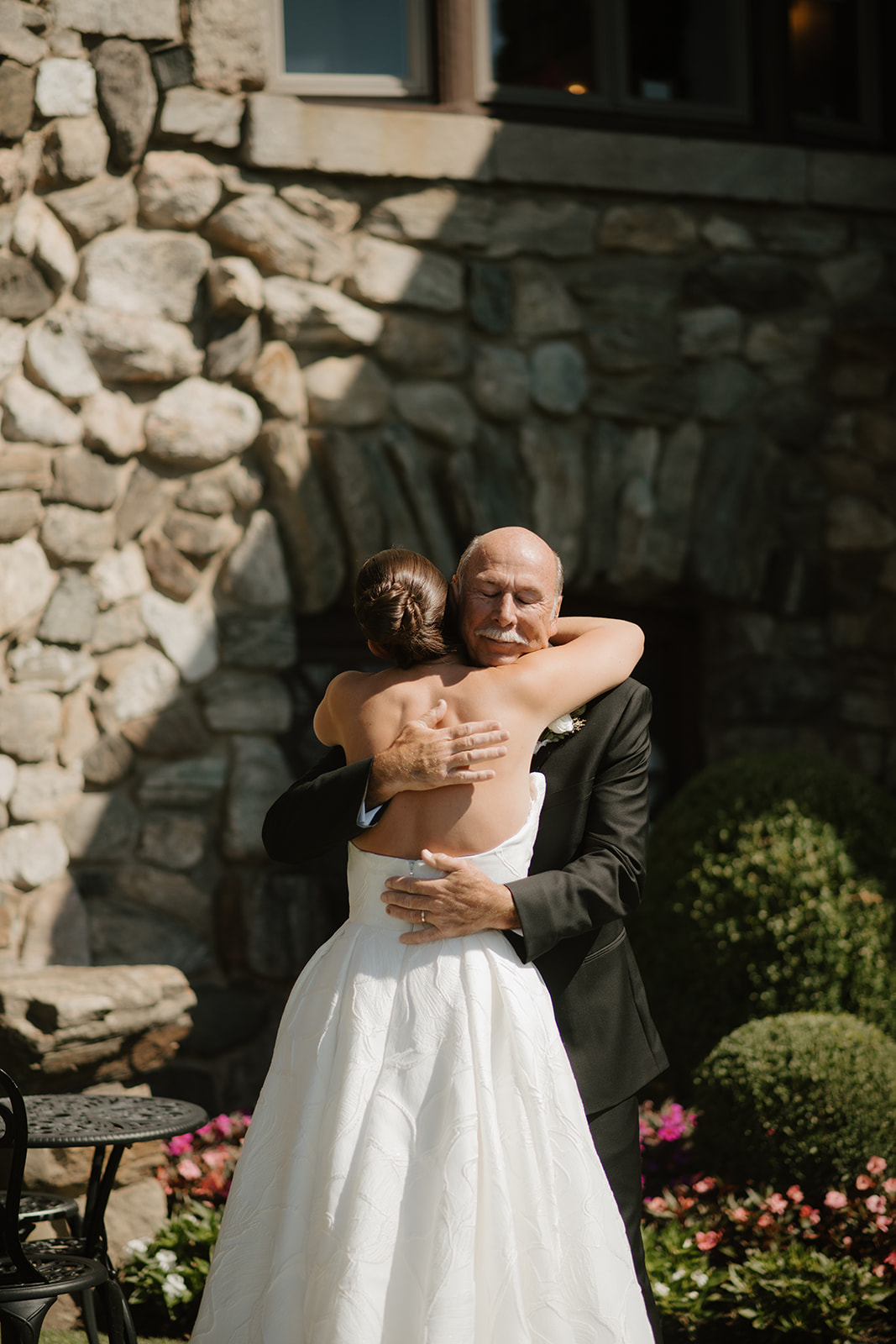 Emotional father closing his eyes while tightly hugging his daughter during their first look.